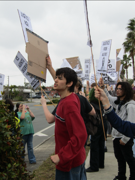 Students hold signs of protest at the front entrance of the school.